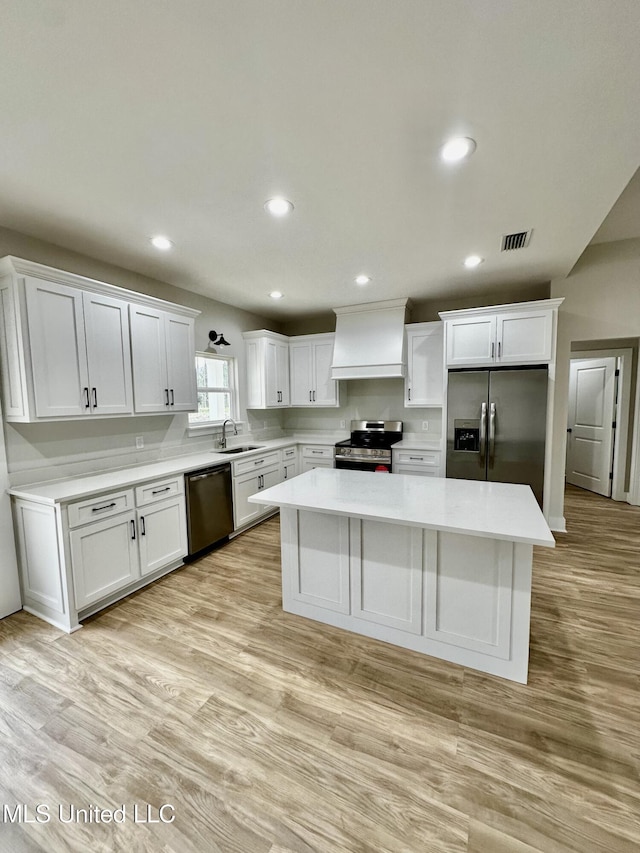 kitchen featuring stainless steel appliances, a kitchen island, white cabinets, and sink