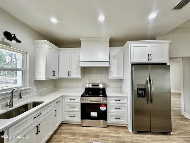 kitchen featuring appliances with stainless steel finishes, light wood-type flooring, custom range hood, sink, and white cabinetry