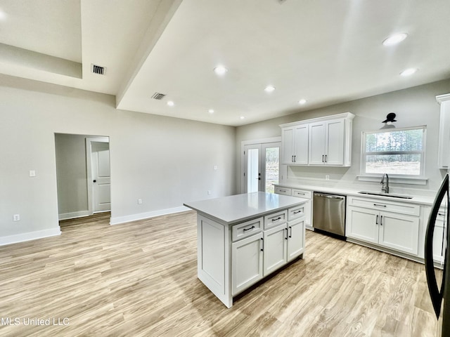 kitchen with light hardwood / wood-style floors, a kitchen island, sink, white cabinetry, and stainless steel dishwasher