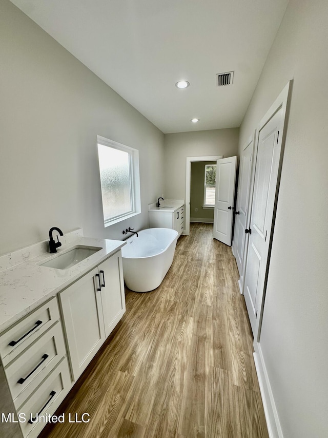 bathroom with hardwood / wood-style flooring, a tub to relax in, and vanity