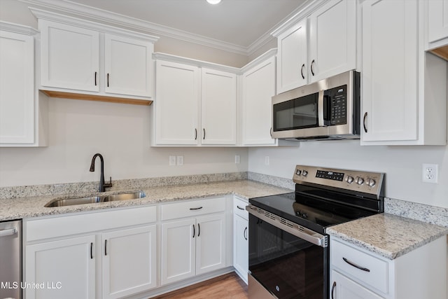 kitchen with white cabinets, a sink, ornamental molding, stainless steel appliances, and light stone counters