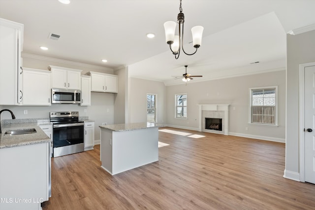 kitchen featuring visible vents, a sink, appliances with stainless steel finishes, crown molding, and ceiling fan with notable chandelier