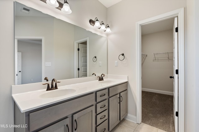 full bathroom with a sink, a walk in closet, tile patterned floors, and double vanity