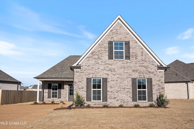 craftsman house with brick siding, a front lawn, fence, and roof with shingles