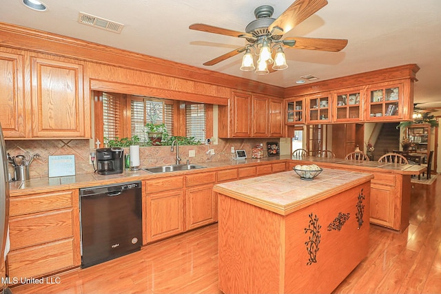 kitchen with tile counters, black dishwasher, visible vents, and a sink