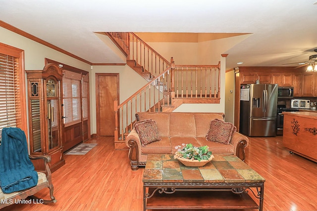 living room with light wood-style floors, a ceiling fan, stairway, and crown molding