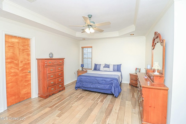 bedroom featuring light wood-style floors, a raised ceiling, crown molding, and a ceiling fan