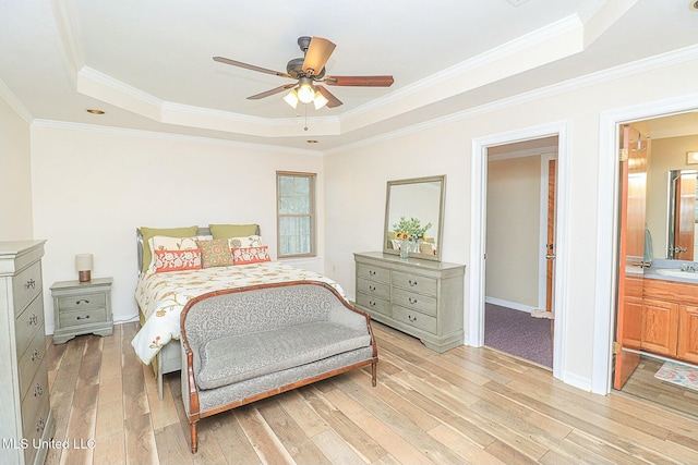 bedroom featuring light wood-type flooring, a raised ceiling, crown molding, and baseboards