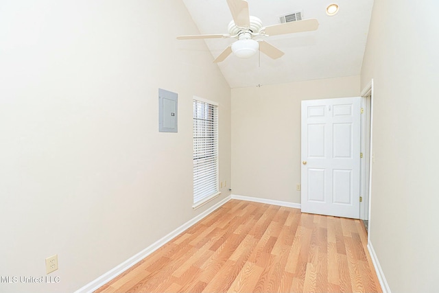 spare room featuring electric panel, baseboards, visible vents, lofted ceiling, and light wood-type flooring