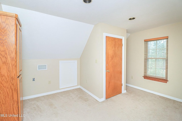 additional living space featuring lofted ceiling, baseboards, visible vents, and light colored carpet