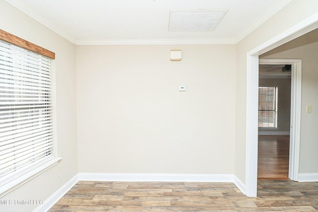 empty room featuring ornamental molding, light wood-type flooring, visible vents, and baseboards