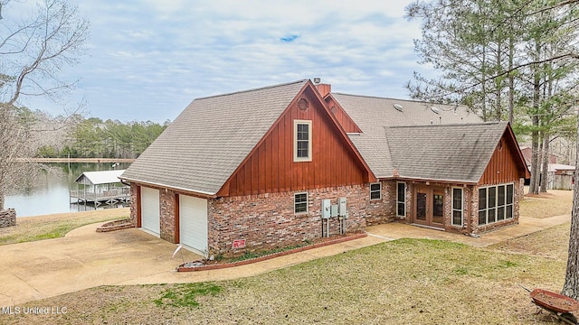 rear view of property with a garage, brick siding, concrete driveway, a lawn, and a chimney