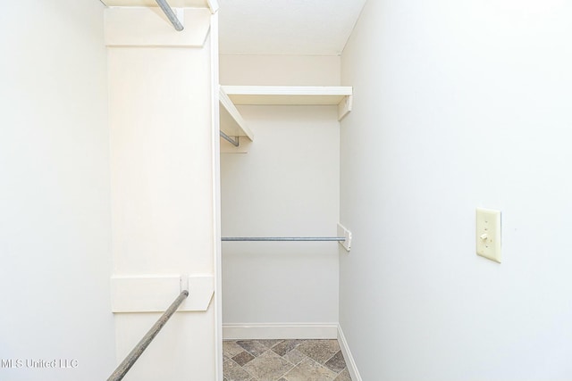 walk in closet with stone finish flooring