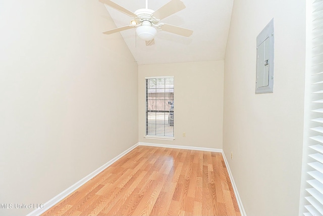 empty room featuring lofted ceiling, a ceiling fan, baseboards, light wood-type flooring, and electric panel