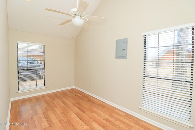 empty room with ceiling fan, baseboards, vaulted ceiling, light wood-type flooring, and electric panel