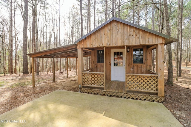 view of outbuilding with a carport, an outdoor structure, and driveway