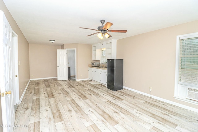 unfurnished living room with light wood-style floors, baseboards, and a ceiling fan