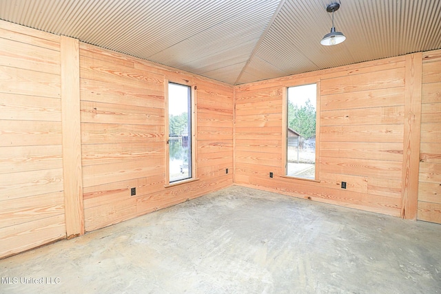 empty room with wooden walls and unfinished concrete floors