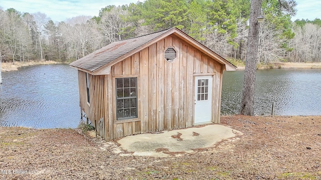 view of outdoor structure featuring a water view, a wooded view, and an outbuilding