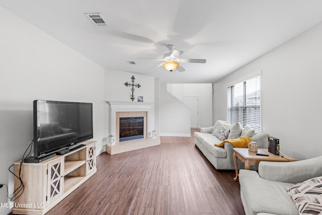 living room featuring dark wood-type flooring, a fireplace, and ceiling fan