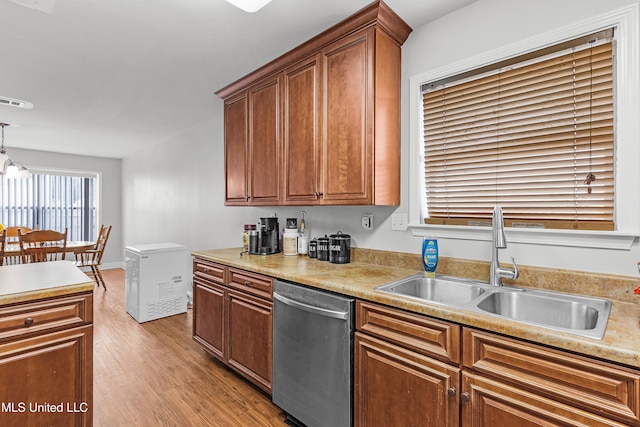 kitchen featuring pendant lighting, light hardwood / wood-style flooring, stainless steel dishwasher, and sink