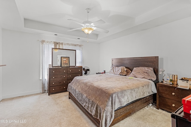 bedroom with ceiling fan, light carpet, and a raised ceiling