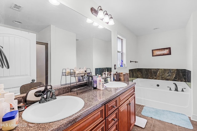 bathroom with a washtub, vanity, and tile patterned flooring