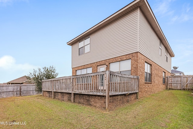 back of property featuring a wooden deck and a yard