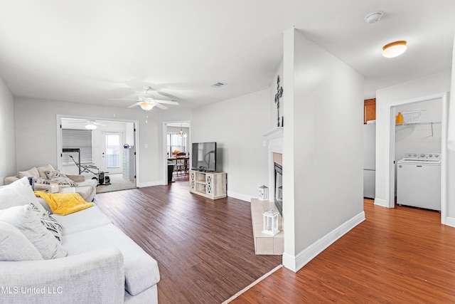 living room featuring hardwood / wood-style flooring, ceiling fan, and washer / dryer