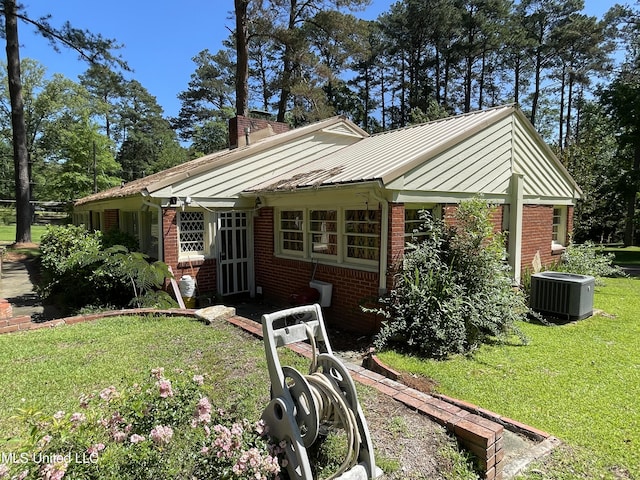 2136 Attala Rd Unit 5247, Kosciusko, MS 39090 - view of front facade with a chimney, a standing seam roof, brick siding, cooling unit, and a front lawn