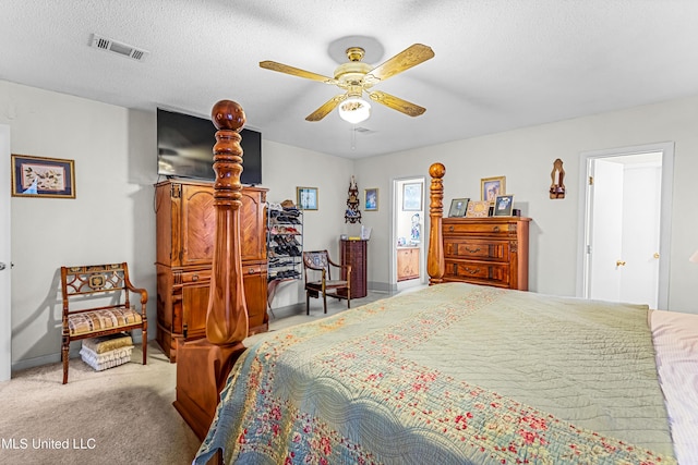 bedroom with ceiling fan, light colored carpet, and a textured ceiling