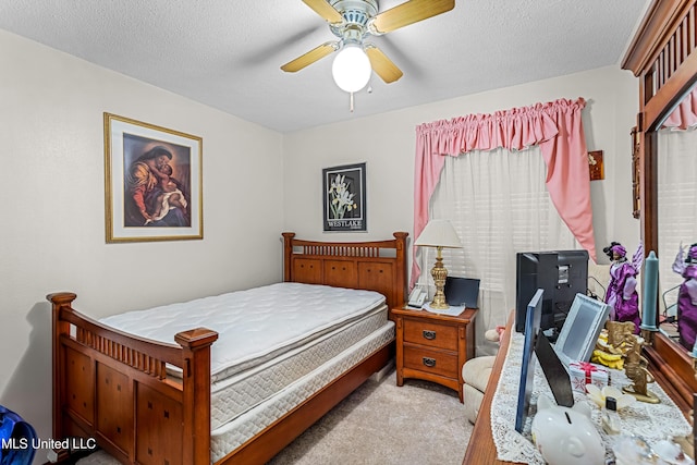 bedroom with a textured ceiling, light colored carpet, and ceiling fan