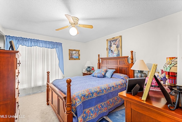 bedroom with ceiling fan, light colored carpet, and a textured ceiling