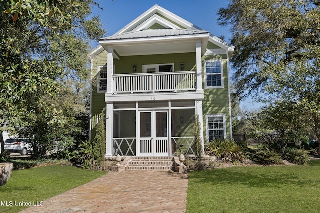 view of front facade featuring metal roof, a sunroom, a front lawn, and a balcony