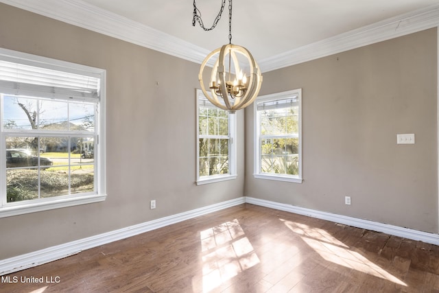 spare room featuring a chandelier, baseboards, wood finished floors, and crown molding