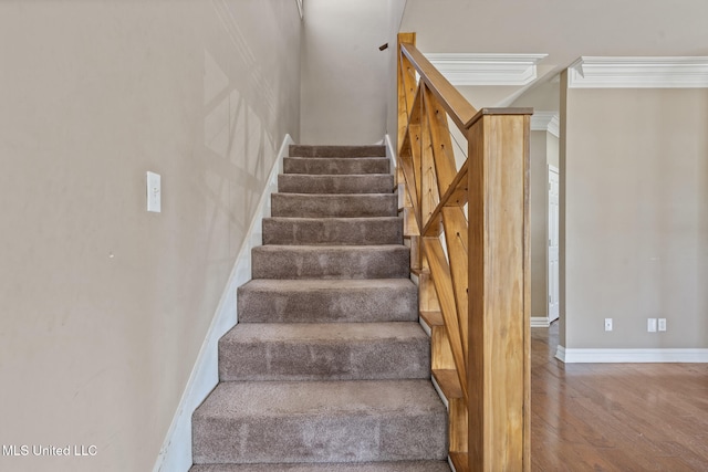 staircase with crown molding, wood finished floors, and baseboards