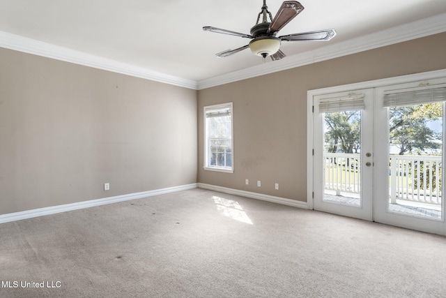 carpeted spare room featuring a healthy amount of sunlight, ceiling fan, crown molding, and french doors