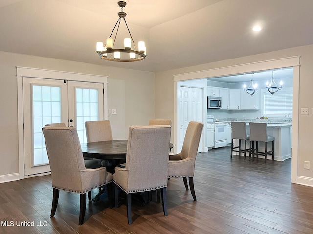 dining area featuring dark wood-type flooring, french doors, sink, and a chandelier