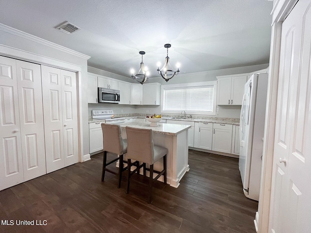 kitchen featuring white appliances, white cabinetry, dark wood-type flooring, and a kitchen island