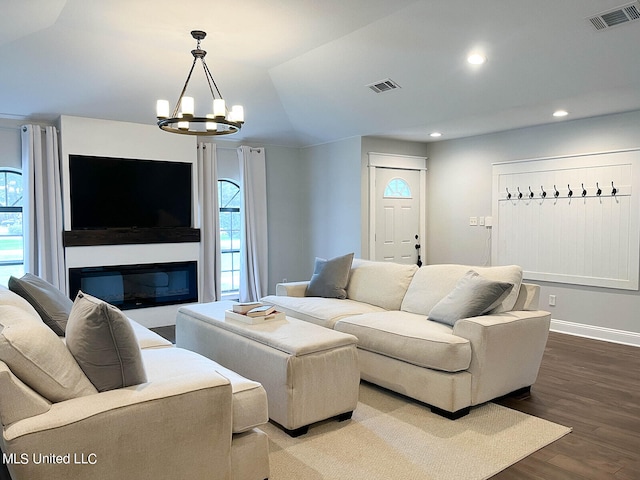 living room featuring hardwood / wood-style flooring, vaulted ceiling, and a chandelier