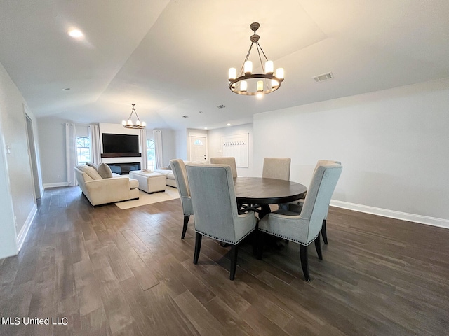 dining room featuring a notable chandelier, lofted ceiling, and dark hardwood / wood-style flooring