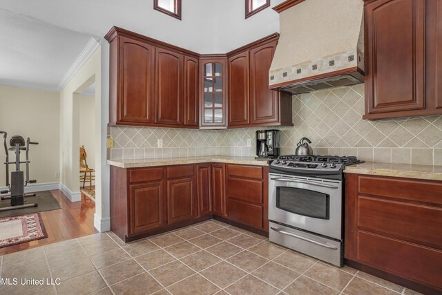 420 N Caribe Pl, Gulfport, MS 39507 - kitchen with premium range hood, stainless steel gas stove, crown molding, backsplash, and glass insert cabinets