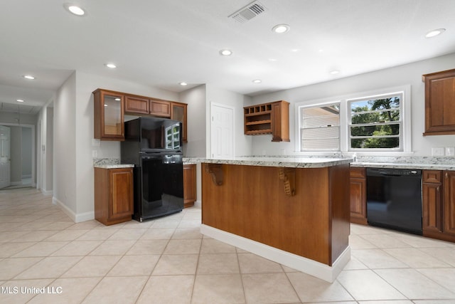 kitchen with a kitchen breakfast bar, a center island, light stone counters, black appliances, and light tile patterned flooring