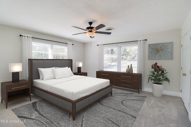 carpeted bedroom featuring ceiling fan and a textured ceiling