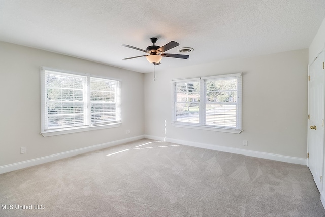 carpeted empty room featuring ceiling fan, plenty of natural light, and a textured ceiling