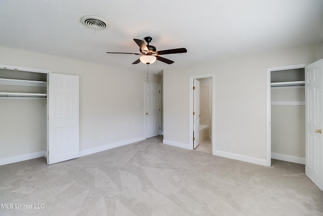 unfurnished bedroom with multiple closets, light colored carpet, ceiling fan, and ensuite bath