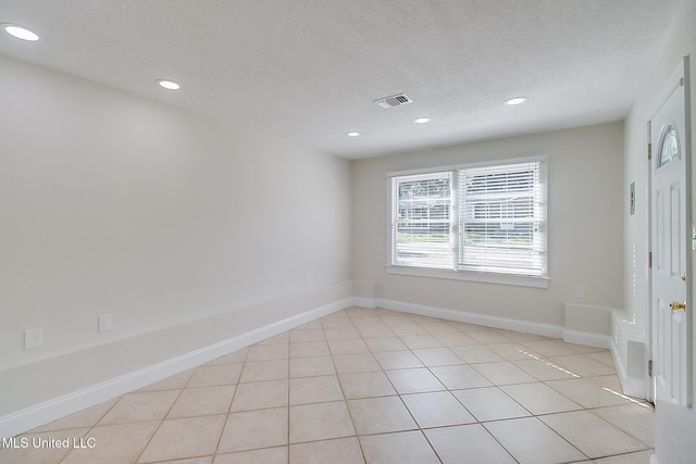 spare room featuring a textured ceiling and light tile patterned floors