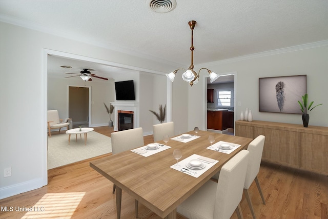 dining room with ceiling fan with notable chandelier, ornamental molding, and light wood-type flooring