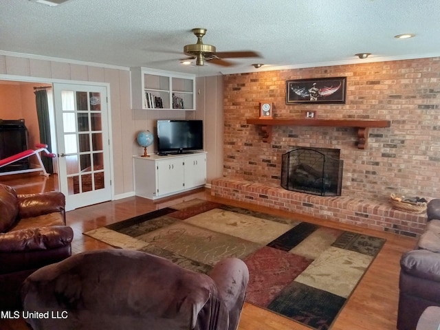 701 W Gresham St, Indianola, MS 38751 - living room with a brick fireplace, wood-type flooring, a textured ceiling, ornamental molding, and ceiling fan