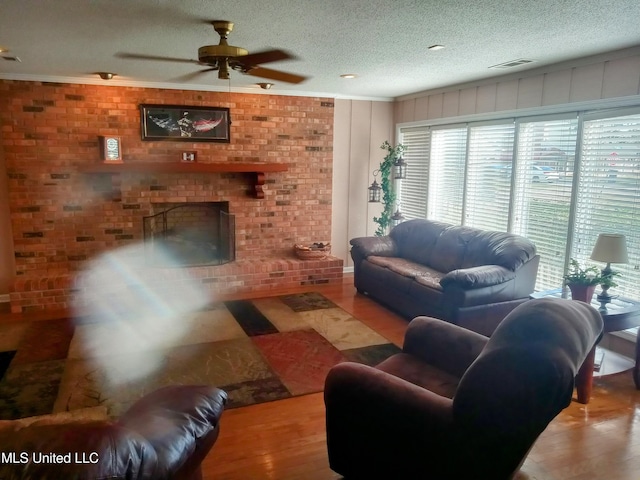 701 W Gresham St, Indianola, MS 38751 - living room featuring a fireplace, light hardwood / wood-style floors, a textured ceiling, and ceiling fan